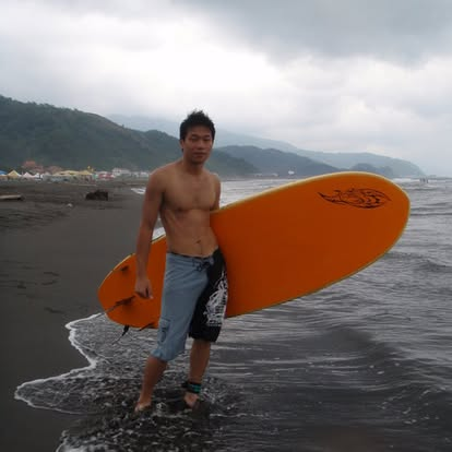 BLAKE 赤裸上身、手拿橘色衝浪板站在海邊的過往生活照